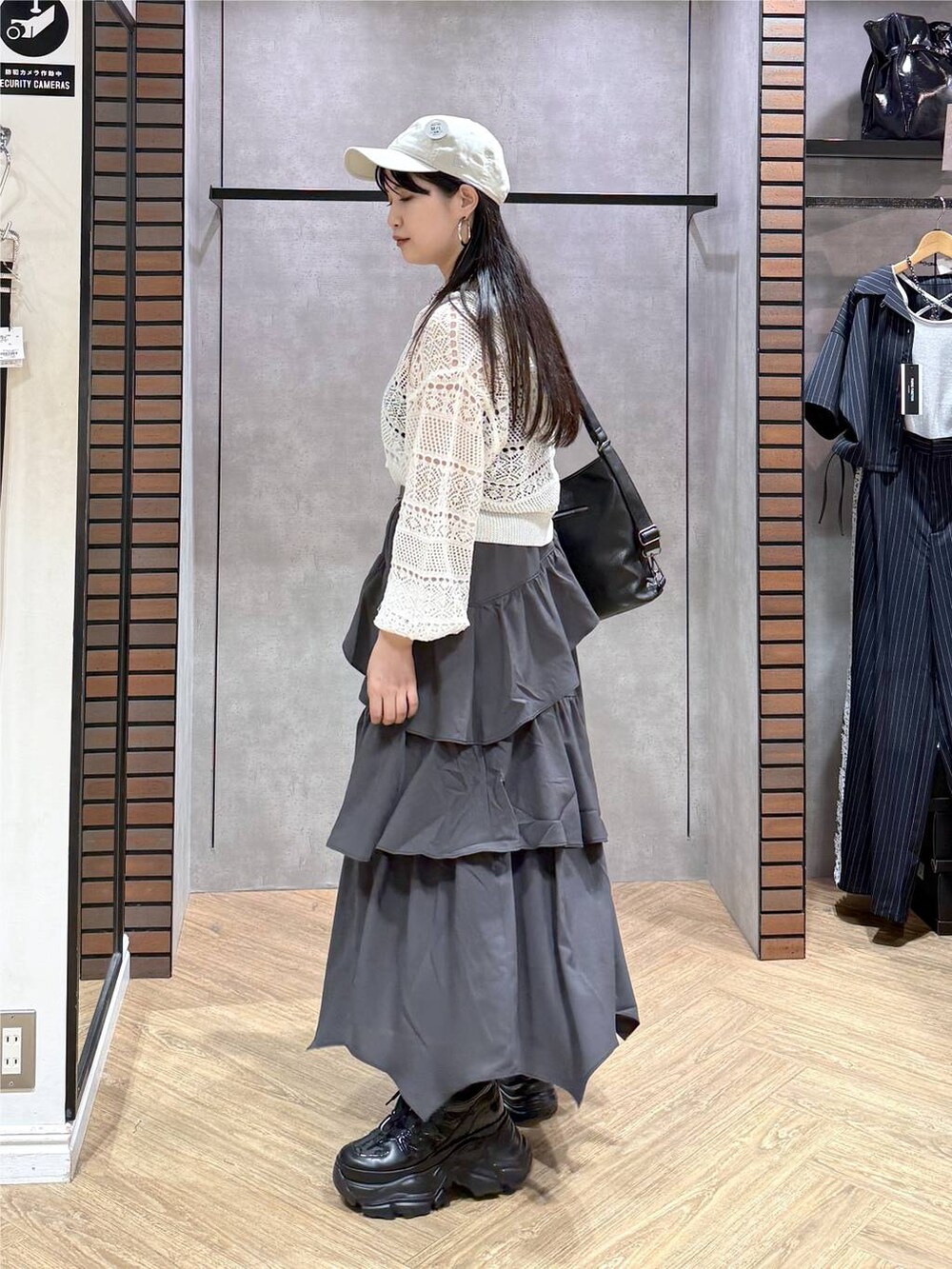 グレー系のスカート、ブラック系のスニーカー、ホワイト系のパーカーを着用したレディースの夏コーディネートの6枚目の写真