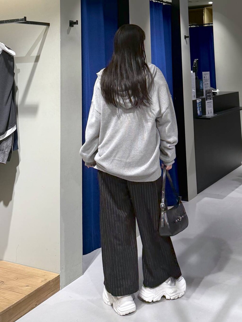 ホワイト系のスニーカー、ブラック系のハンドバッグ、ホワイト系のニット/セーターを着用したレディースの冬コーディネートの2枚目の写真