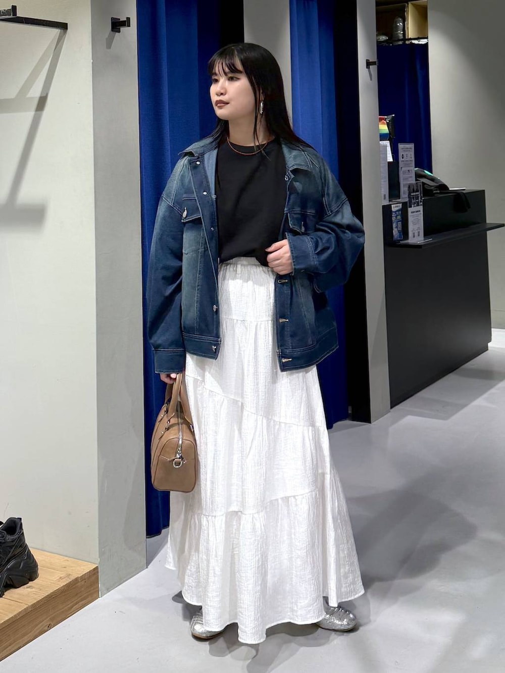 ブラック系のスウェット、ブラウン系のボストンバッグ、ブルー系のブルゾンを着用したレディースの春コーディネートの4枚目の写真