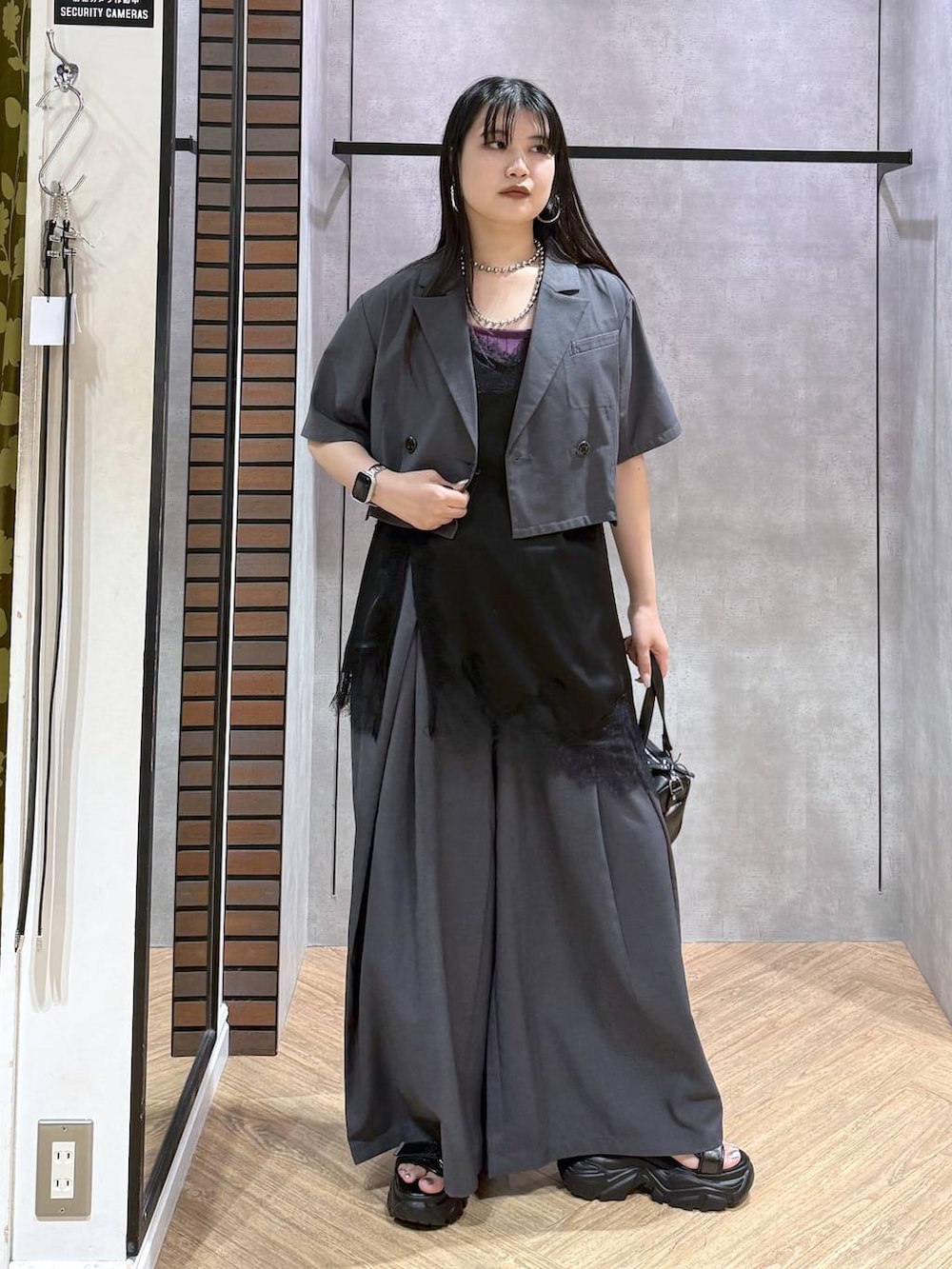 ブラック系のデニムパンツ、ブラック系のショルダーバッグ、ブラック系のチュニックを着用したレディースの夏コーディネートの3枚目の写真