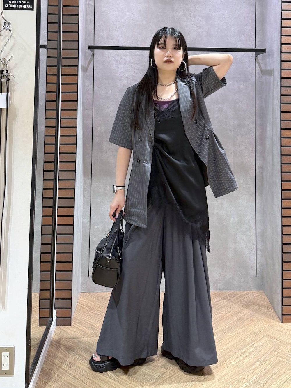 ブラック系のデニムパンツ、ブラック系のショルダーバッグ、ブラック系のチュニックを着用したレディースの夏コーディネートの2枚目の写真