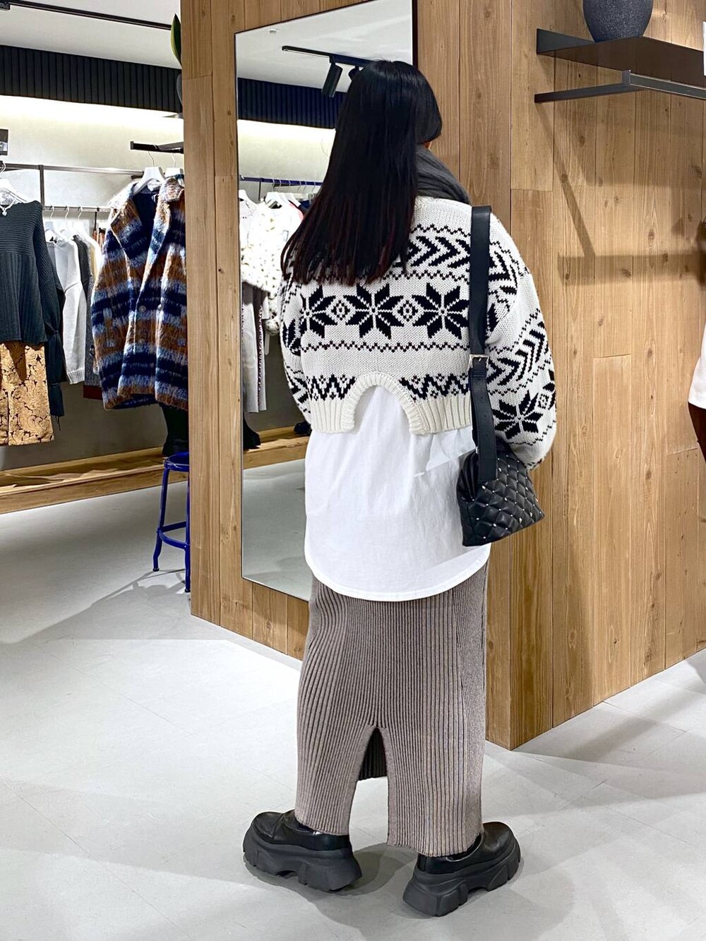 ブラック系のブーツ、ホワイト系のTシャツ/カットソー、ブラック系のショルダーバッグを着用したレディースの冬コーディネートの3枚目の写真