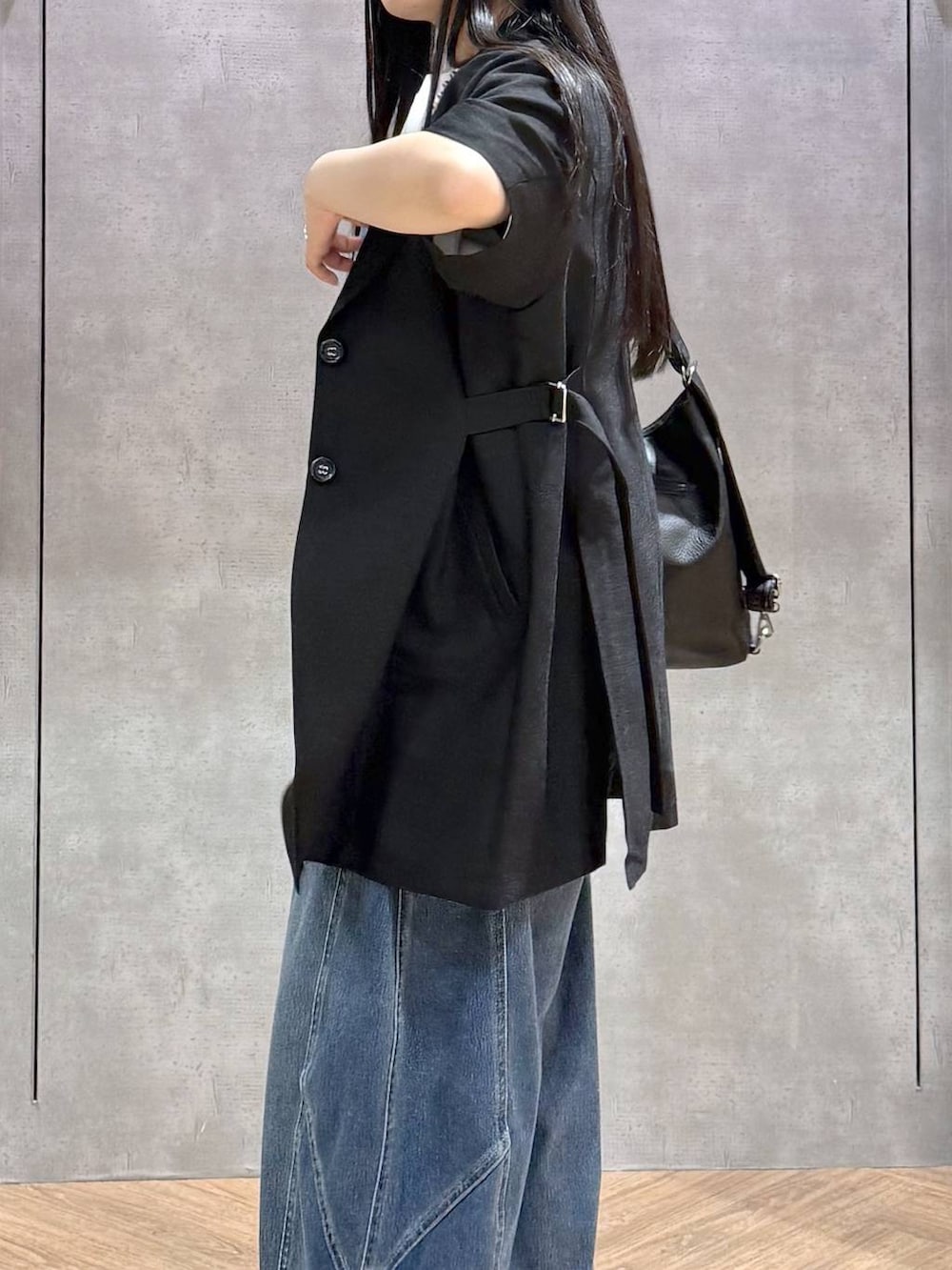 ブラック系のショルダーバッグ、ブルー系のデニムパンツ、ブラック系のサンダルを着用したレディースの春コーディネートの3枚目の写真