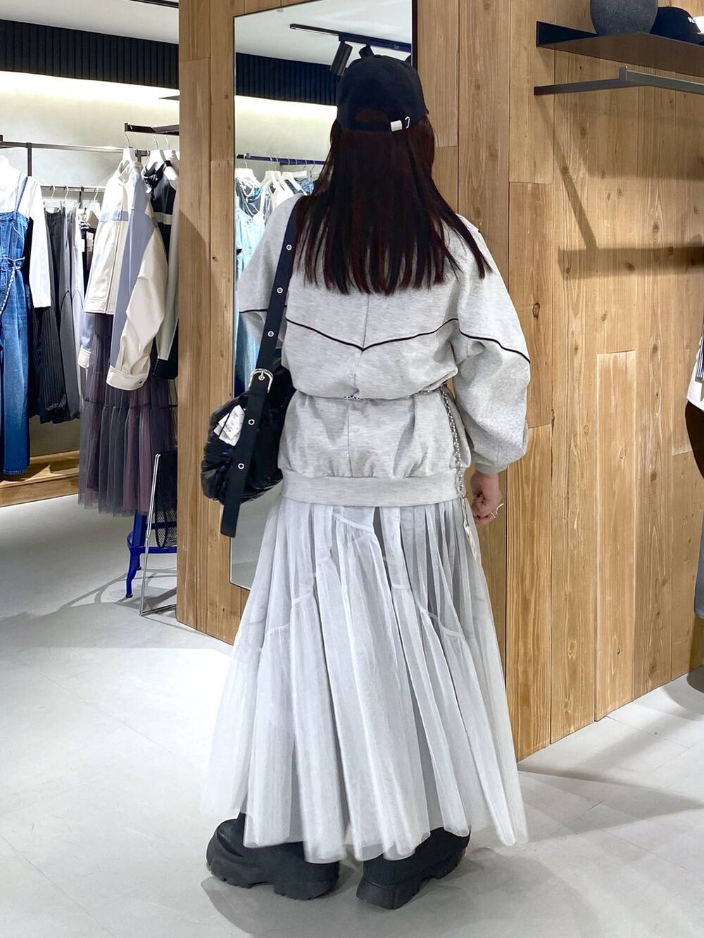 ブラック系のショルダーバッグ、グレー系のスウェット、ホワイト系のワンピースを着用したレディースの春コーディネートの2枚目の写真