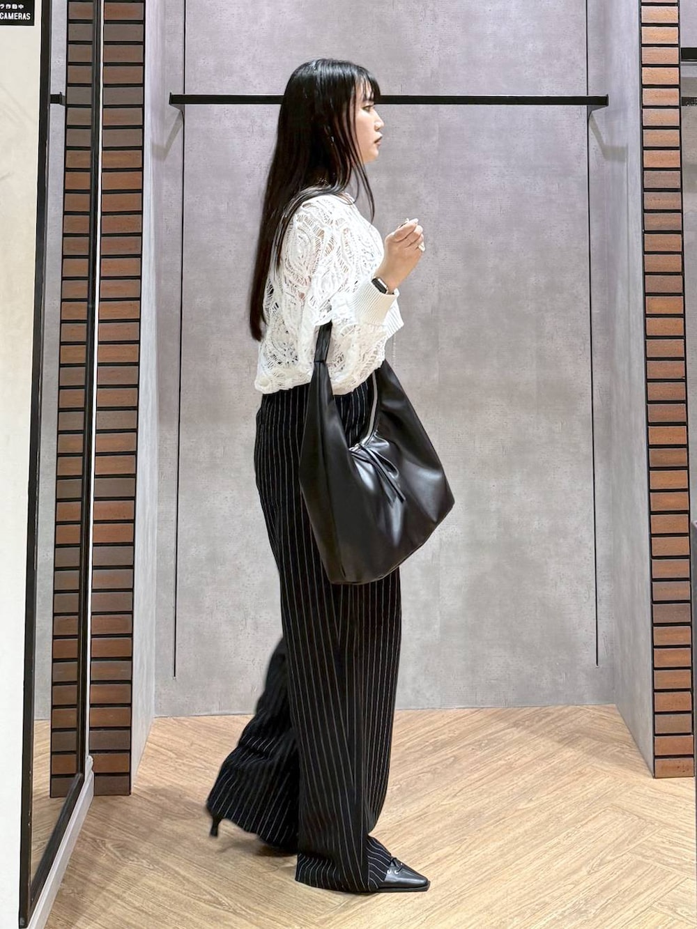 ブラック系のキャミソール、ホワイト系のカーディガン/ボレロ、ブラック系のトートバッグを着用したレディースの春コーディネートの3枚目の写真