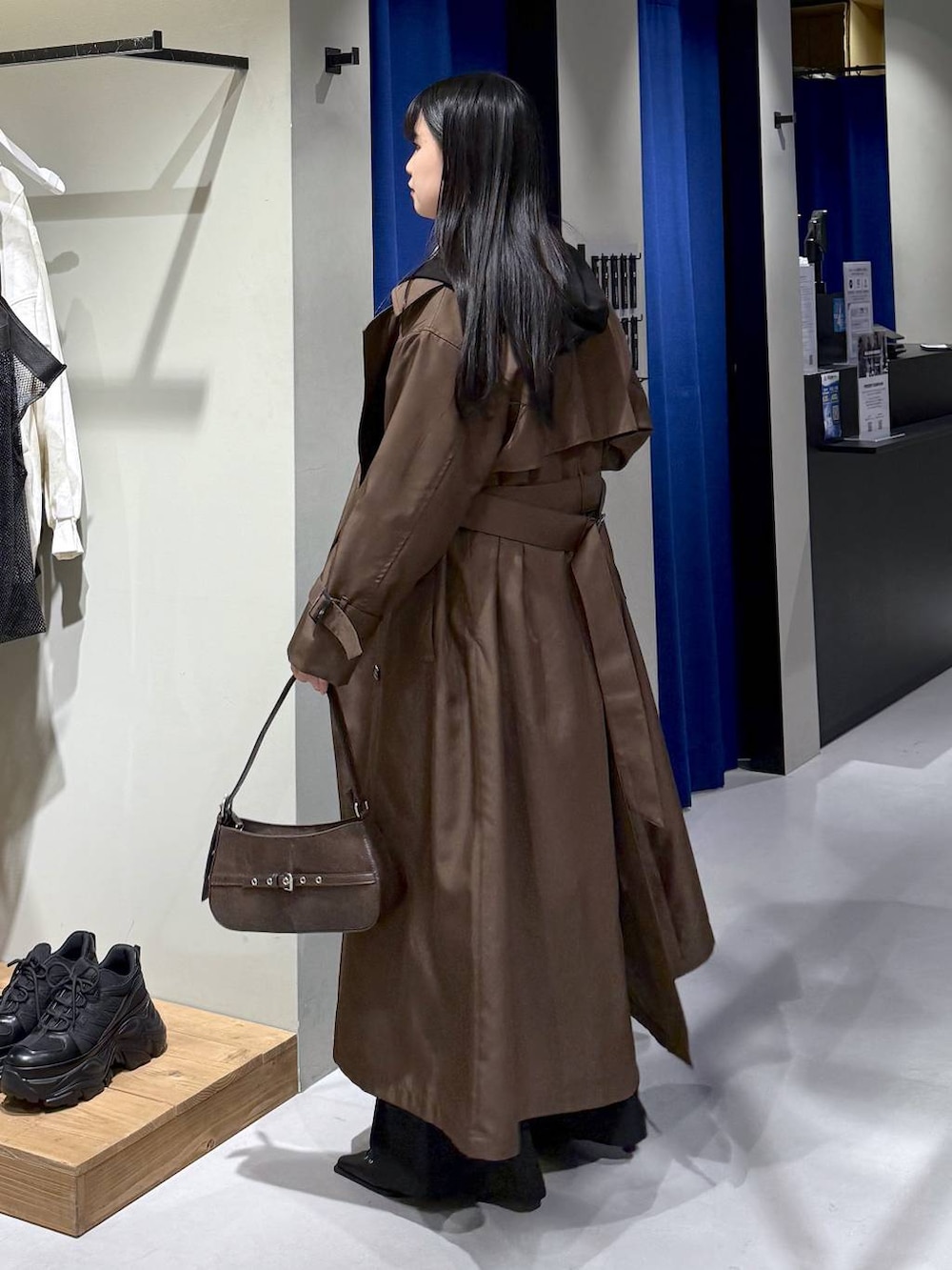 ブラック系のデニムパンツ、ブラウン系のトレンチコート、ブラウン系のハンドバッグを着用したレディースの冬コーディネートの3枚目の写真