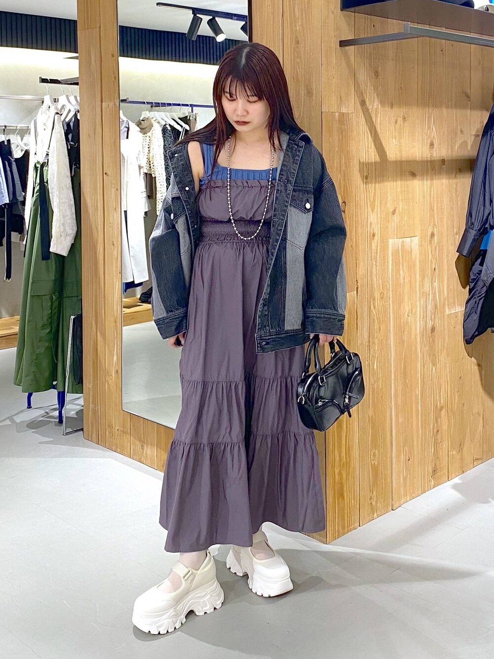 ブルー系のタンクトップ、ブラック系のデニムジャケット、ブラック系のボストンバッグを着用したレディースの春コーディネートの7枚目の写真