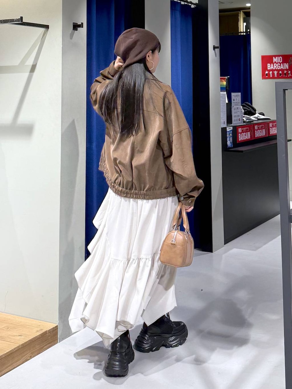 ブラック系のブーツ、ベージュ系のスカート、ブラウン系のボストンバッグを着用したレディースの春コーディネートの4枚目の写真