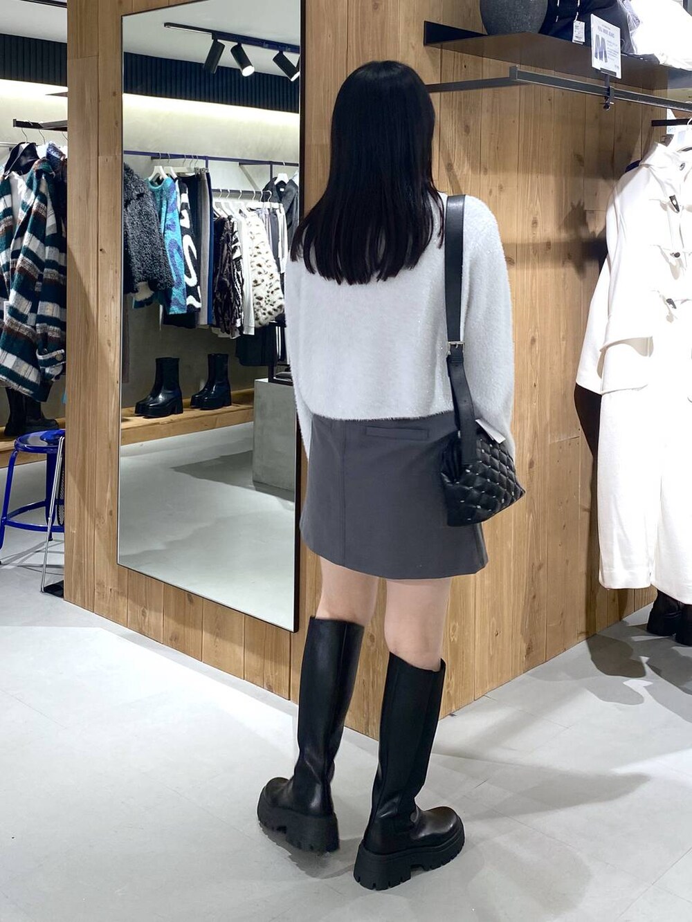 ブラック系のブーツ、ブラック系のショルダーバッグ、ホワイト系のニット/セーターを着用したレディースの冬コーディネートの2枚目の写真