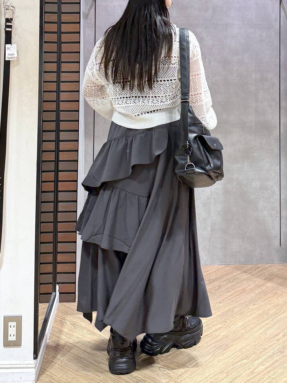 グレー系のスカート、ブラック系のスニーカー、ホワイト系のパーカーを着用したレディースの夏コーディネートの2枚目の写真