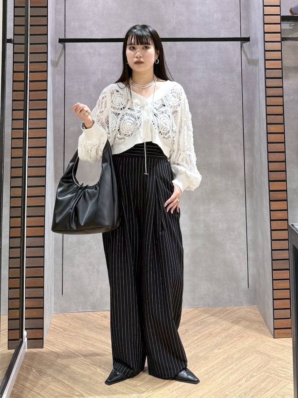 ブラック系のキャミソール、ホワイト系のカーディガン/ボレロ、ブラック系のトートバッグを着用したレディースの春コーディネートの8枚目の写真
