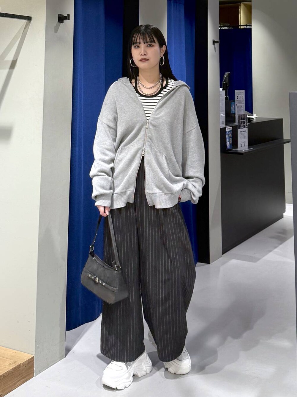 ホワイト系のスニーカー、ブラック系のハンドバッグ、ホワイト系のニット/セーターを着用したレディースの冬コーディネートの6枚目の写真