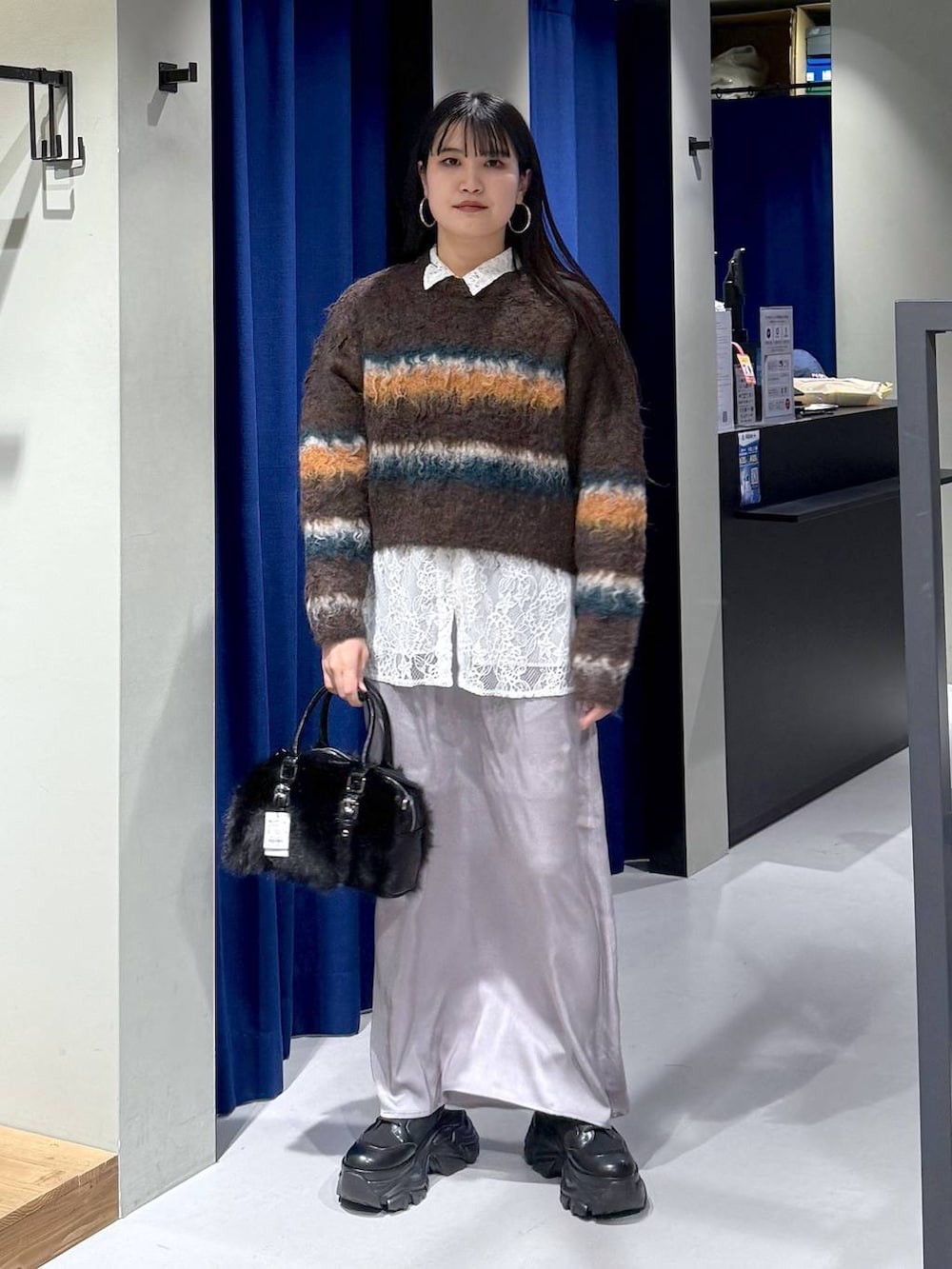 ブラック系のブーツ、ブラウン系のボストンバッグ、ホワイト系のシャツ/ブラウスを着用したレディースの冬コーディネートの3枚目の写真