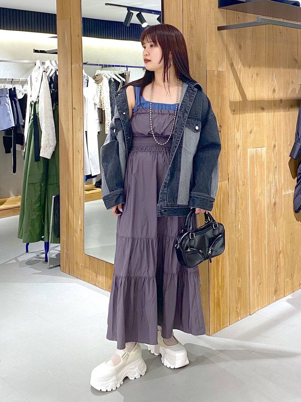 ブルー系のタンクトップ、ブラック系のデニムジャケット、ブラック系のボストンバッグを着用したレディースの春コーディネートの2枚目の写真