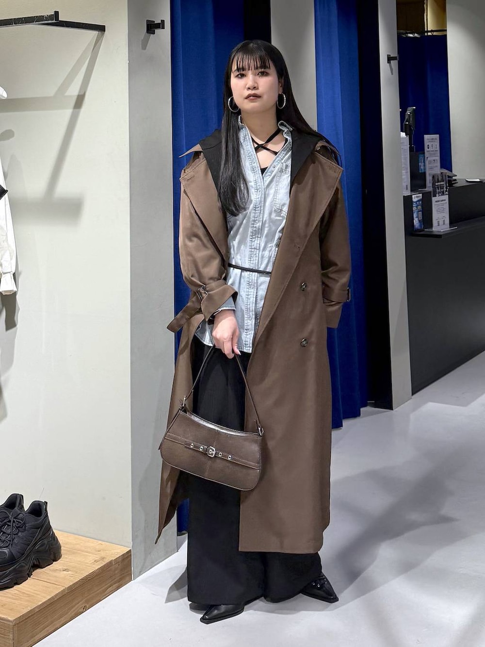 ブラック系のデニムパンツ、ブラウン系のトレンチコート、ブラウン系のハンドバッグを着用したレディースの冬コーディネートの6枚目の写真