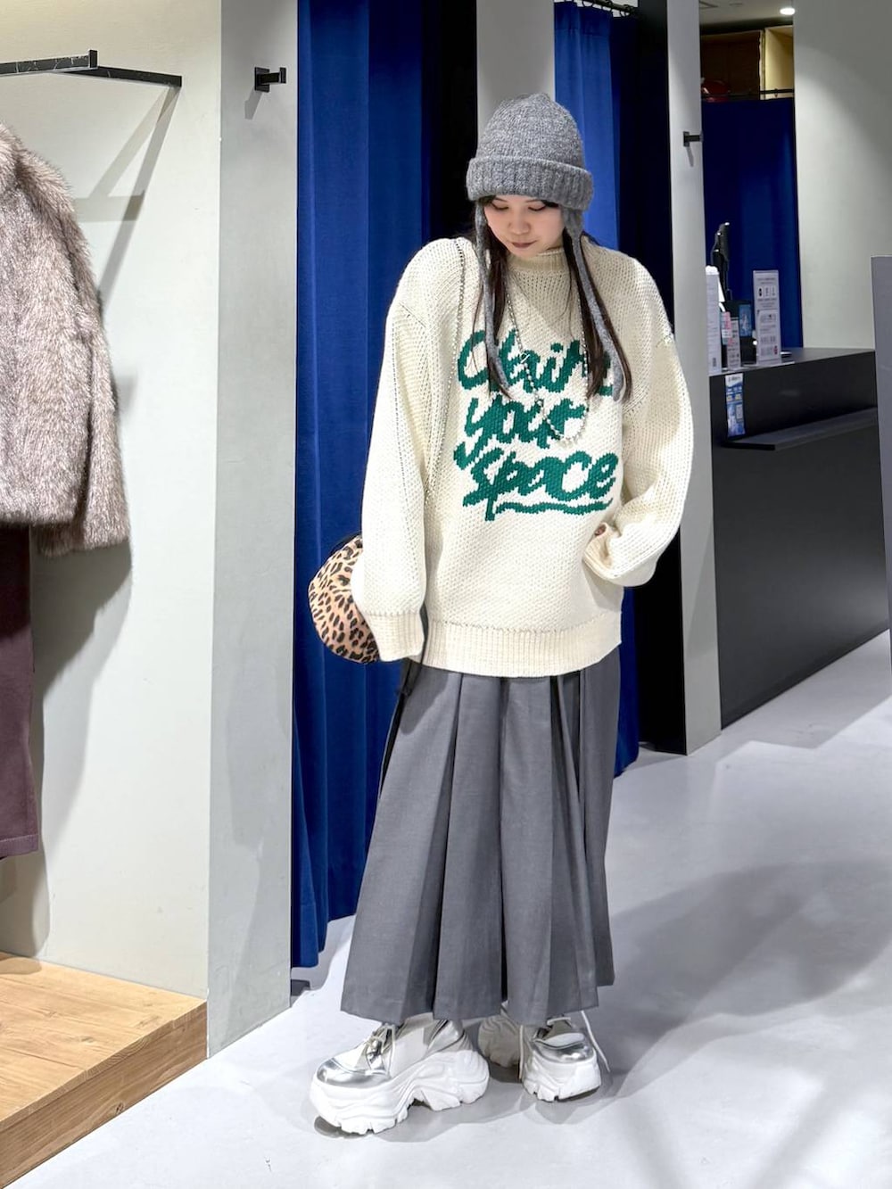 ホワイト系のブーツ、ホワイト系のニット/セーター、グレー系のスカートを着用したレディースの冬コーディネートの2枚目の写真