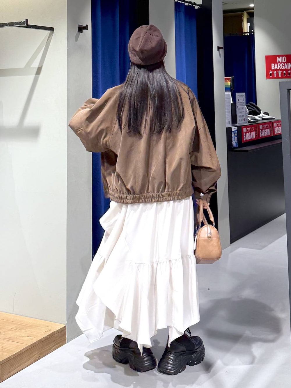 ブラック系のブーツ、ベージュ系のスカート、ブラウン系のボストンバッグを着用したレディースの春コーディネートの6枚目の写真