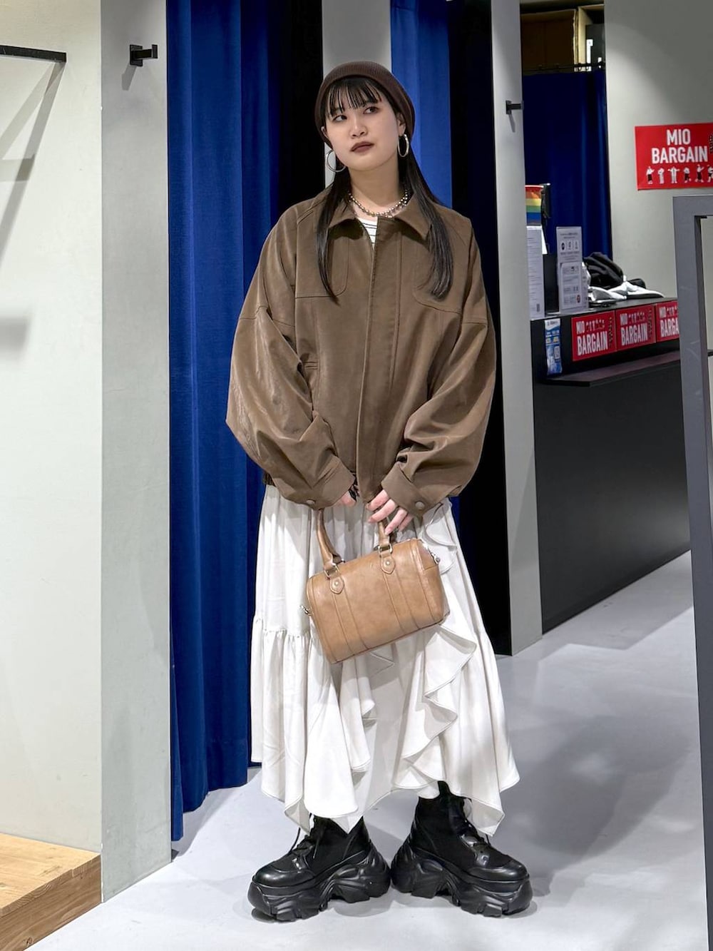 ブラック系のブーツ、ベージュ系のスカート、ブラウン系のボストンバッグを着用したレディースの春コーディネートの9枚目の写真