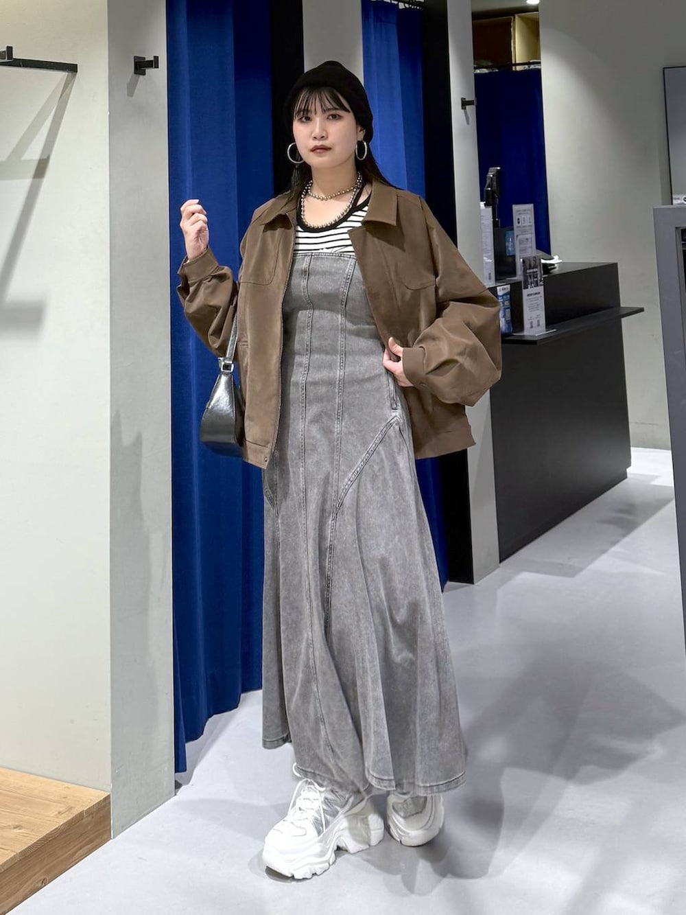 ホワイト系のスニーカー、ブラック系のハンドバッグ、ホワイト系のニット/セーターを着用したレディースの春コーディネートの5枚目の写真