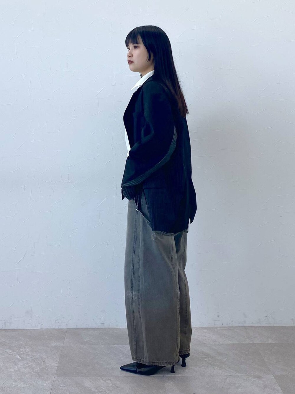 ブラック系のテーラードジャケット、ホワイト系のポロシャツを着用したレディースの冬コーディネートの4枚目の写真