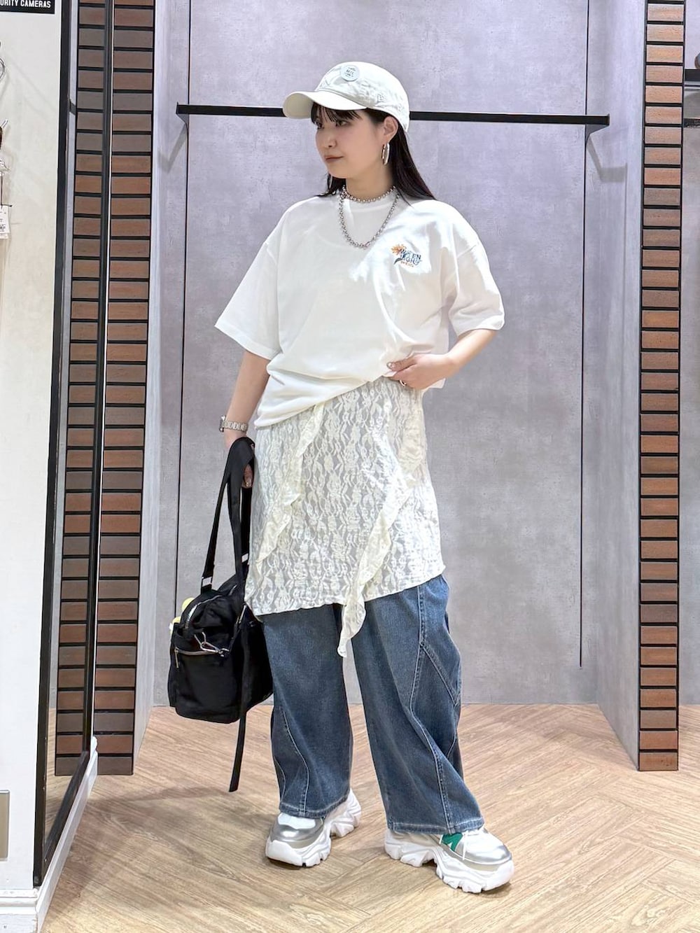 ホワイト系のスニーカー、ブラック系のボストンバッグ、ブルー系のデニムパンツを着用したレディースの春コーディネートの2枚目の写真