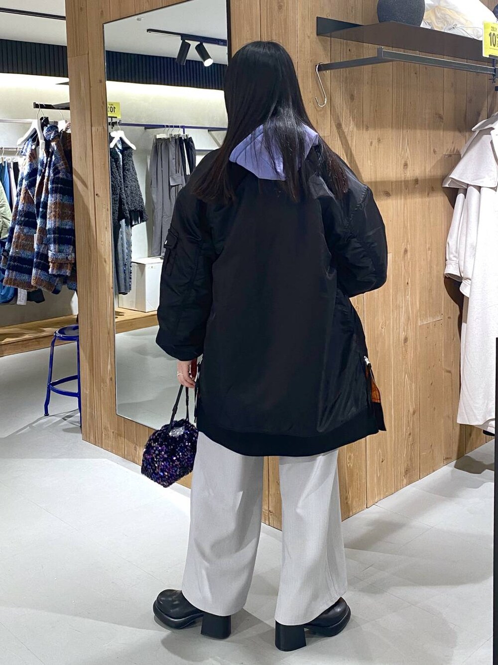 グレー系のスラックス、ブラック系のブーツ、ブラック系のショルダーバッグを着用したレディースの冬コーディネートの2枚目の写真