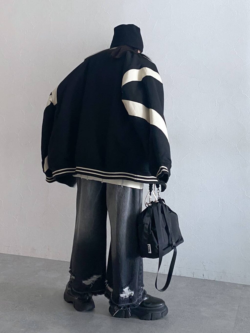 ブラック系のデニムパンツ、ブラック系のスタジャン、ブラック系のショルダーバッグを着用したレディースの秋コーディネートの4枚目の写真