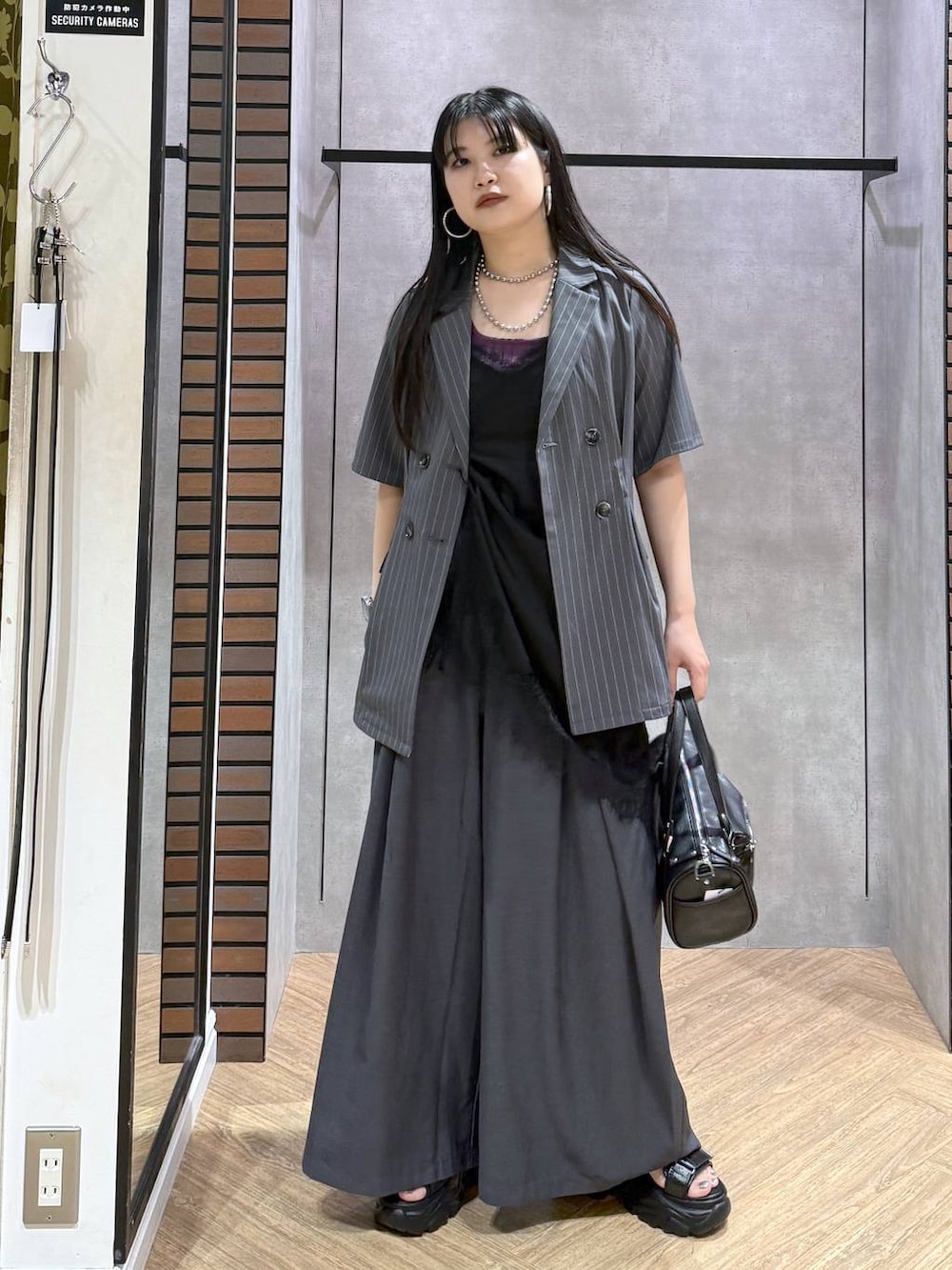 ブラック系のデニムパンツ、ブラック系のショルダーバッグ、ブラック系のチュニックを着用したレディースの夏コーディネートの5枚目の写真