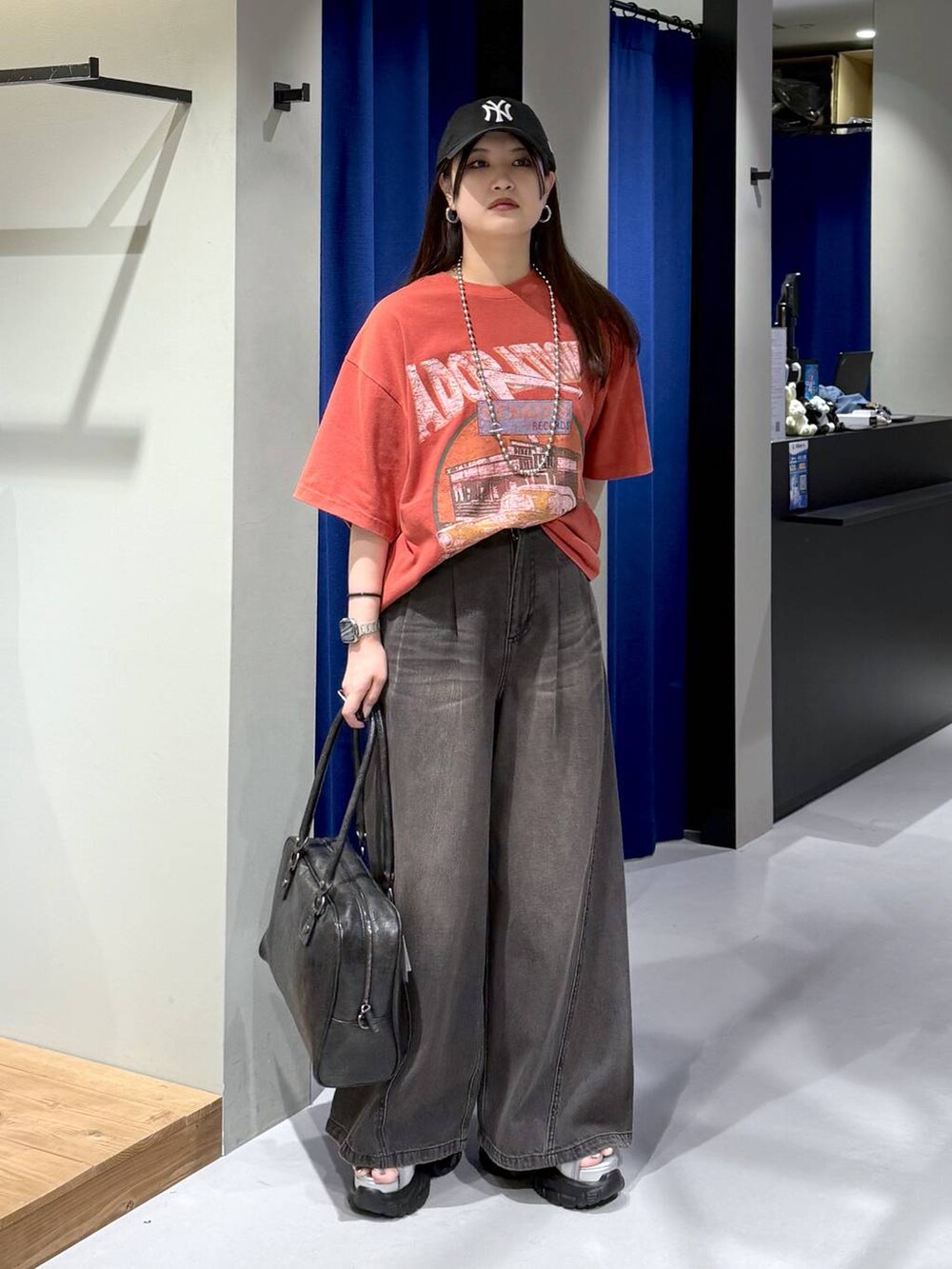 ブラック系のデニムパンツ、ブラック系のボストンバッグ、グレー系のサンダルを着用したレディースの夏コーディネートの5枚目の写真