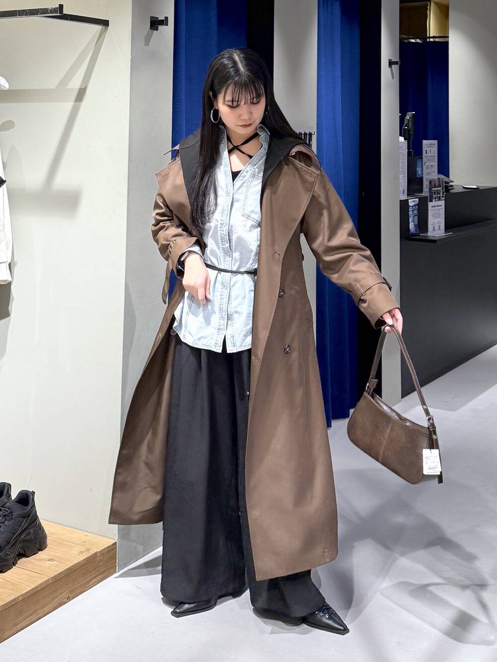 ブラック系のデニムパンツ、ブラウン系のトレンチコート、ブラウン系のハンドバッグを着用したレディースの冬コーディネートの4枚目の写真