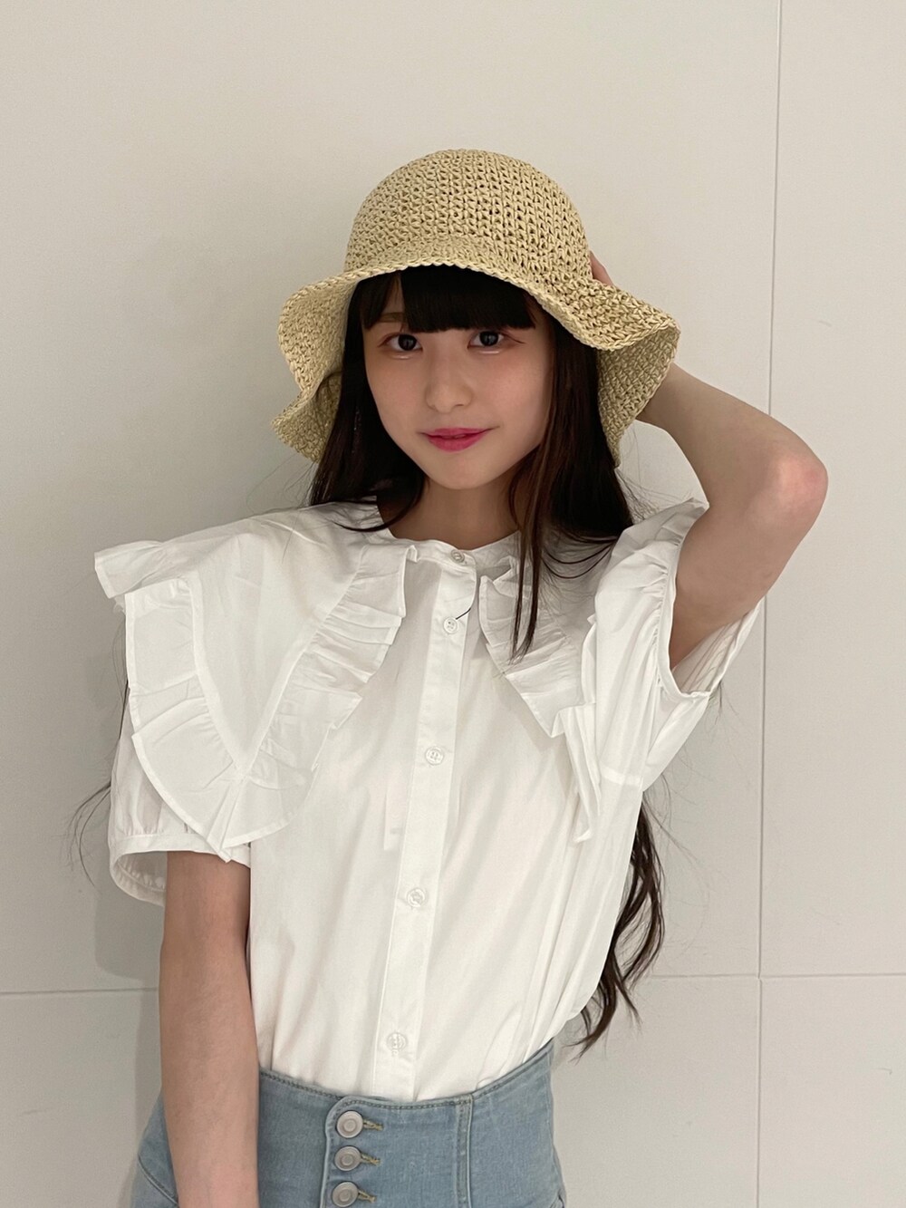 ベージュ系のショルダーバッグ、ブルー系のデニムパンツ、ホワイト系のサンダルを着用したレディースの夏コーディネートの2枚目の写真