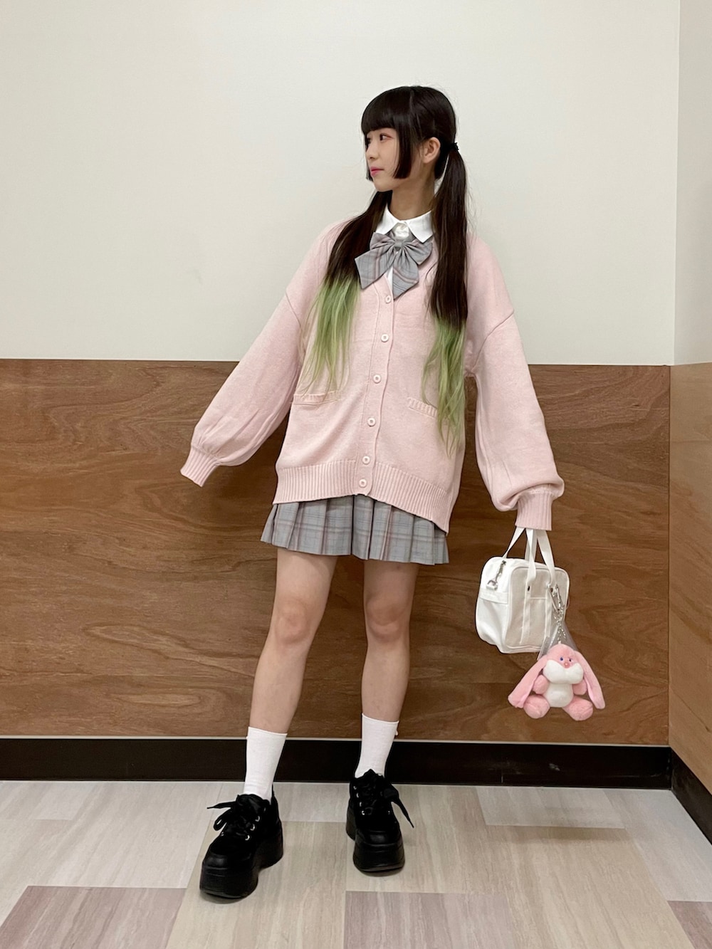 グレー系のスカート、ブラック系のスニーカー、ピンク系のカーディガン/ボレロを着用したレディースの秋コーディネートの3枚目の写真