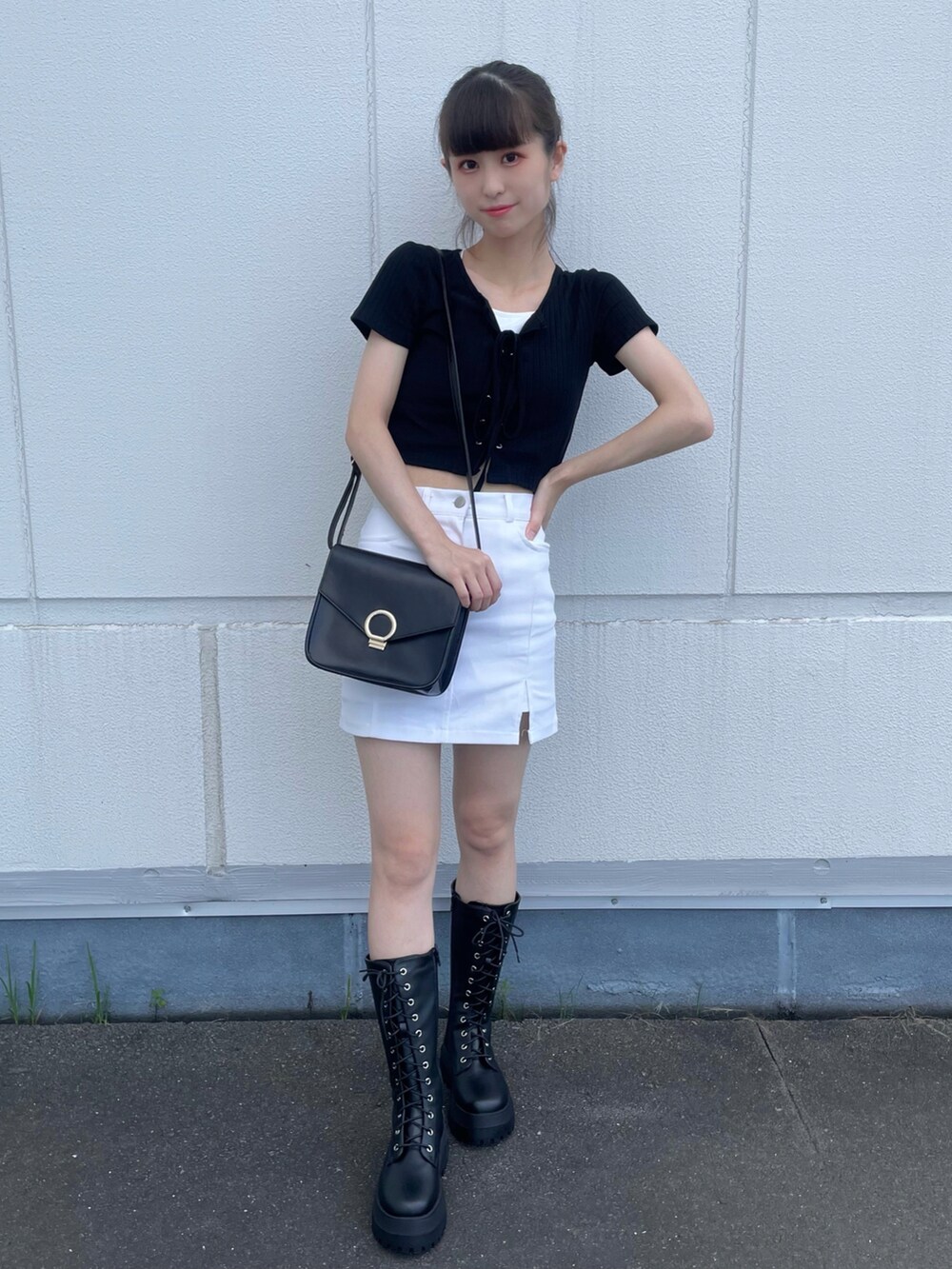 ブラック系のTシャツ/カットソー、ホワイト系のスカート、ブラック系のブーツを着用したレディースの夏コーディネートの2枚目の写真