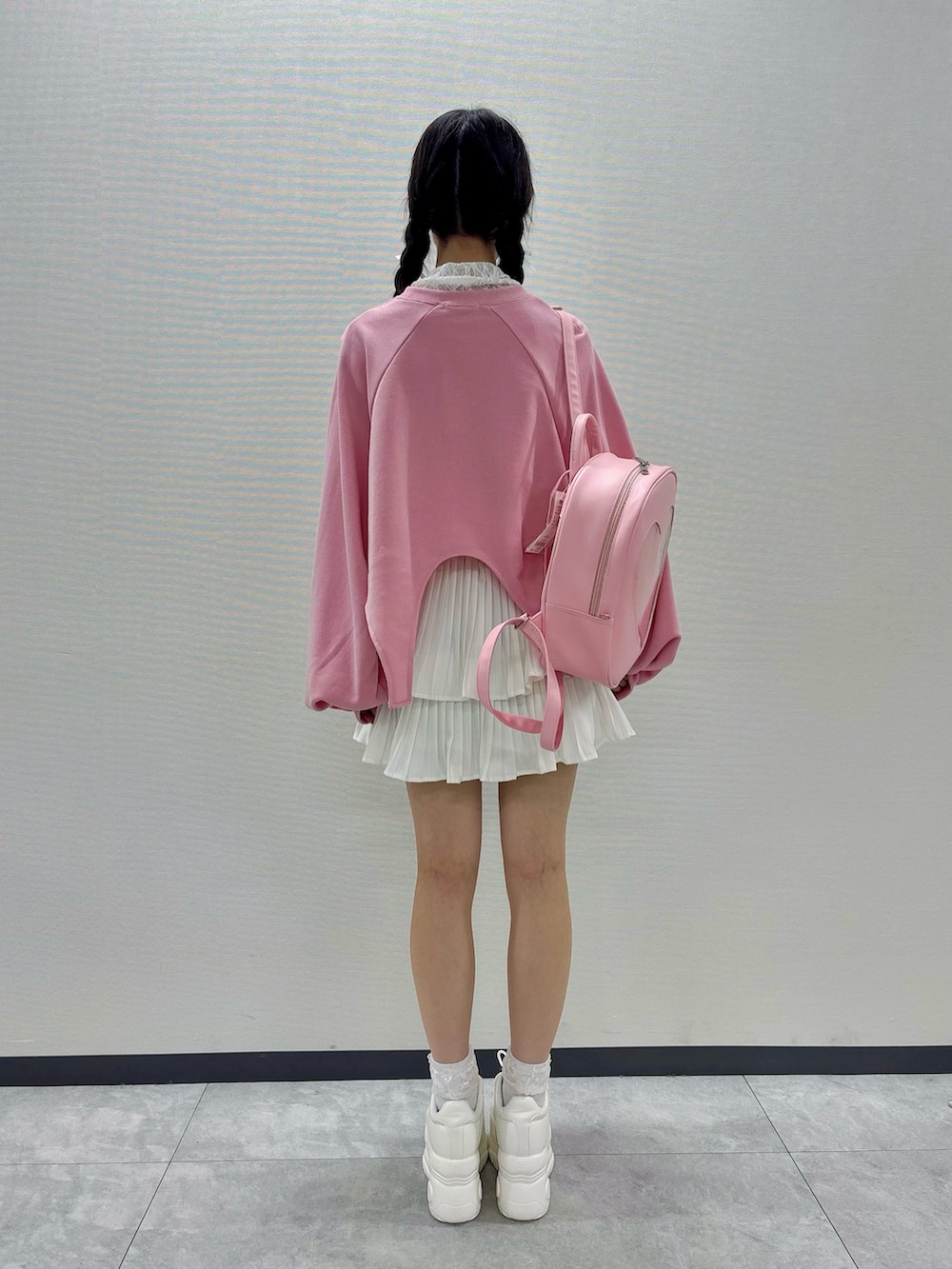 ピンク系のスウェット、ホワイト系のスニーカー、ピンク系のバックパック/リュックを着用したレディースの秋コーディネートの3枚目の写真