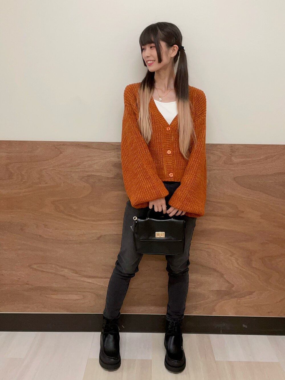 ブラック系のショルダーバッグ、ブラック系のブーツ、ブラック系のデニムパンツを着用したレディースの秋コーディネートの2枚目の写真