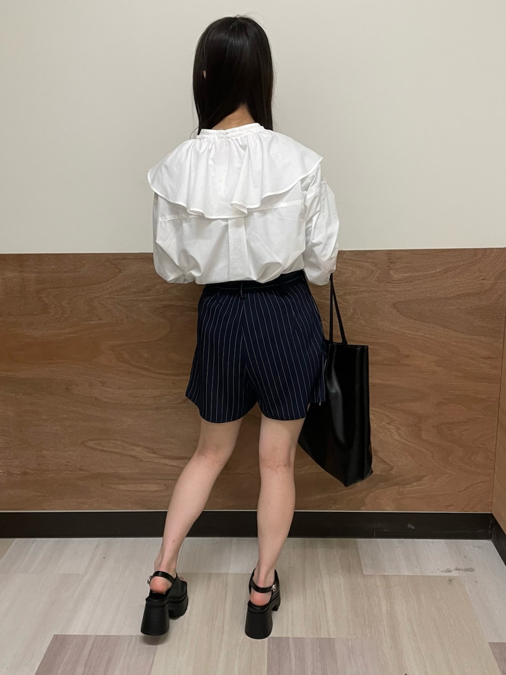 ブルー系のスラックス、ブラック系のトートバッグ、ホワイト系のシャツ/ブラウスを着用したレディースの春コーディネートの3枚目の写真