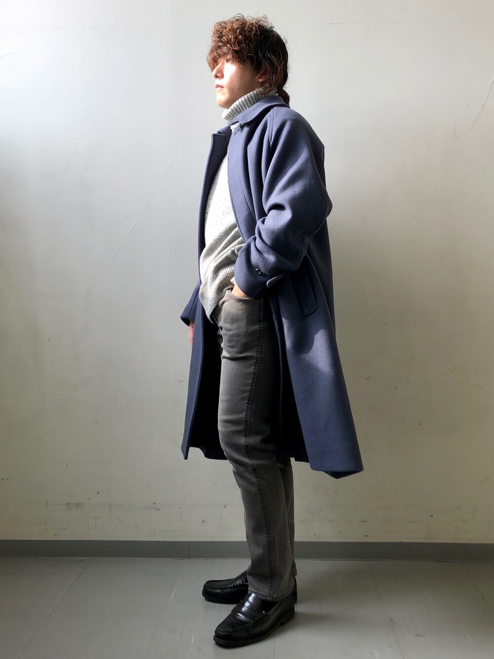 ブルー系のステンカラーコート、グレー系のニット/セーター、ブラック系のその他パンツを着用したメンズの冬コーディネートの3枚目の写真