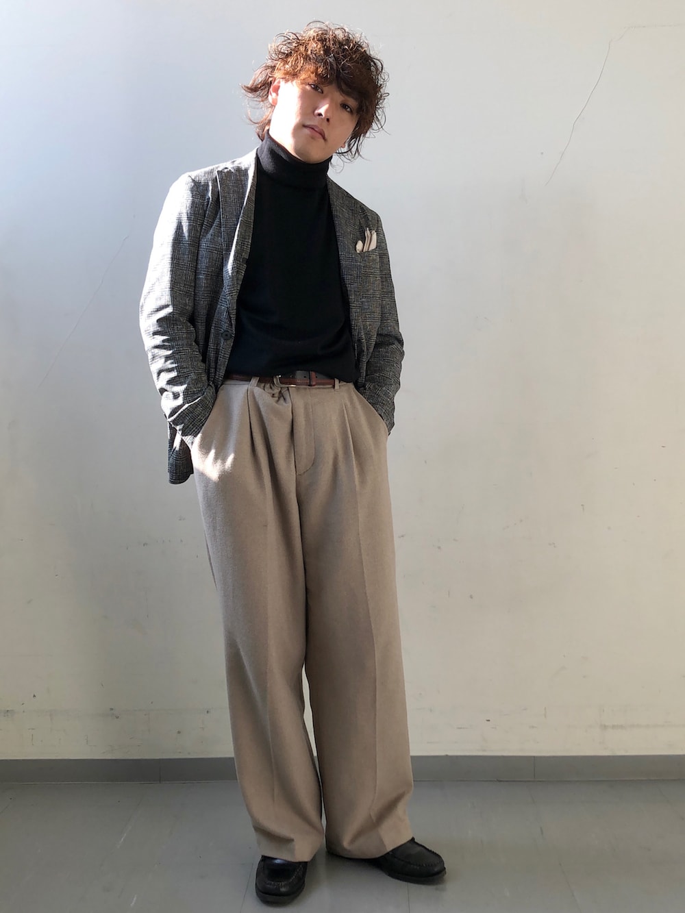 ブラック系のスーツジャケット、ブラック系のニット/セーター、ベージュ系のその他パンツを着用したメンズの冬コーディネートの3枚目の写真