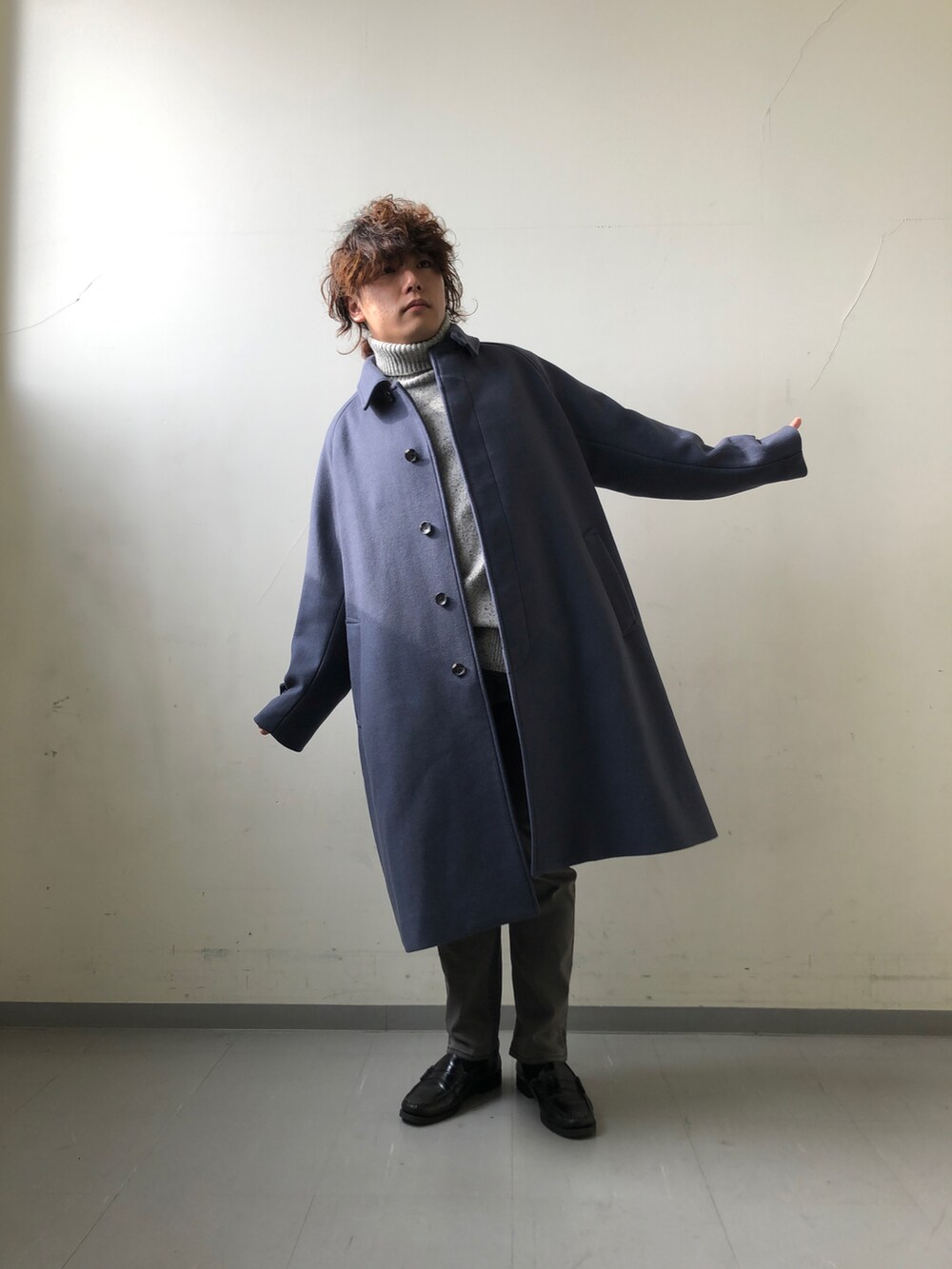 ブルー系のステンカラーコート、グレー系のニット/セーター、ブラック系のその他パンツを着用したメンズの冬コーディネートの2枚目の写真