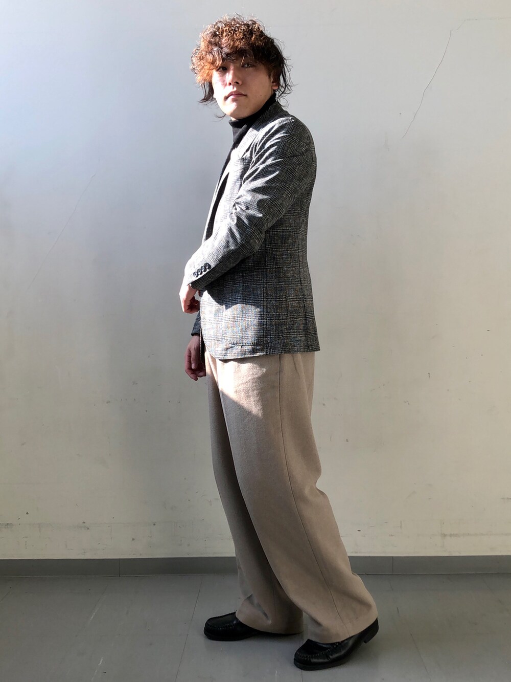 ブラック系のスーツジャケット、ブラック系のニット/セーター、ベージュ系のその他パンツを着用したメンズの冬コーディネートの2枚目の写真