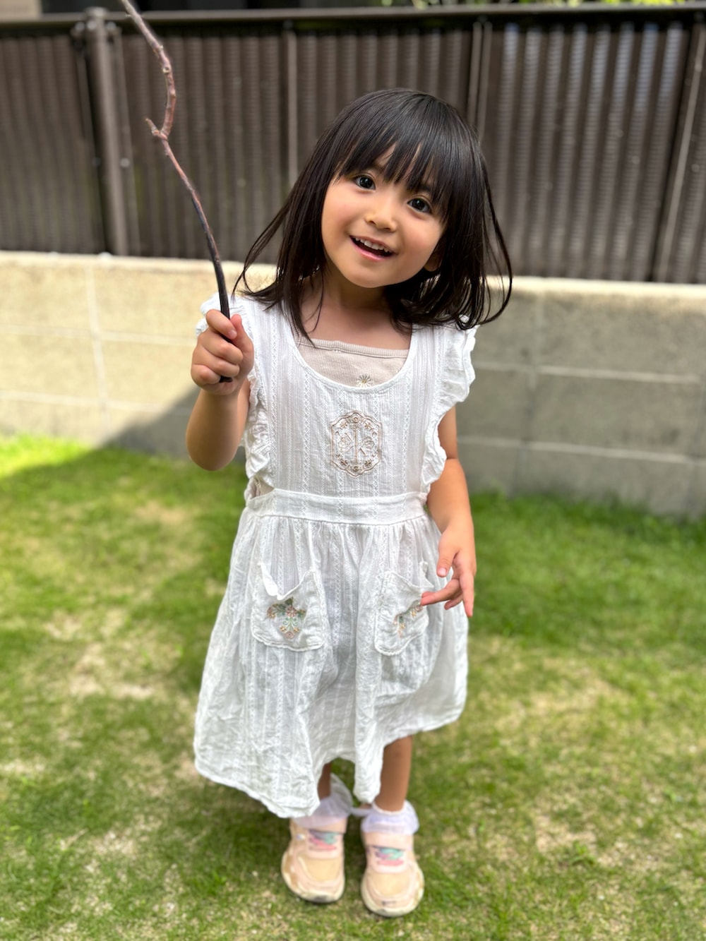 ピンク系のスニーカー、ホワイト系のワンピースを着用したキッズの夏コーディネートの2枚目の写真