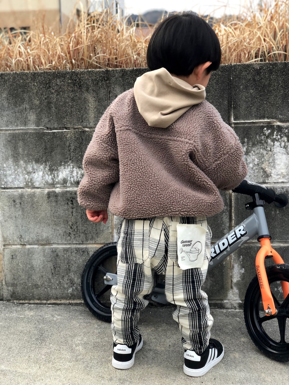 ブラウン系のブルゾン、ベージュ系のパーカー、ホワイト系のチノパンツを着用したキッズの冬コーディネートの2枚目の写真