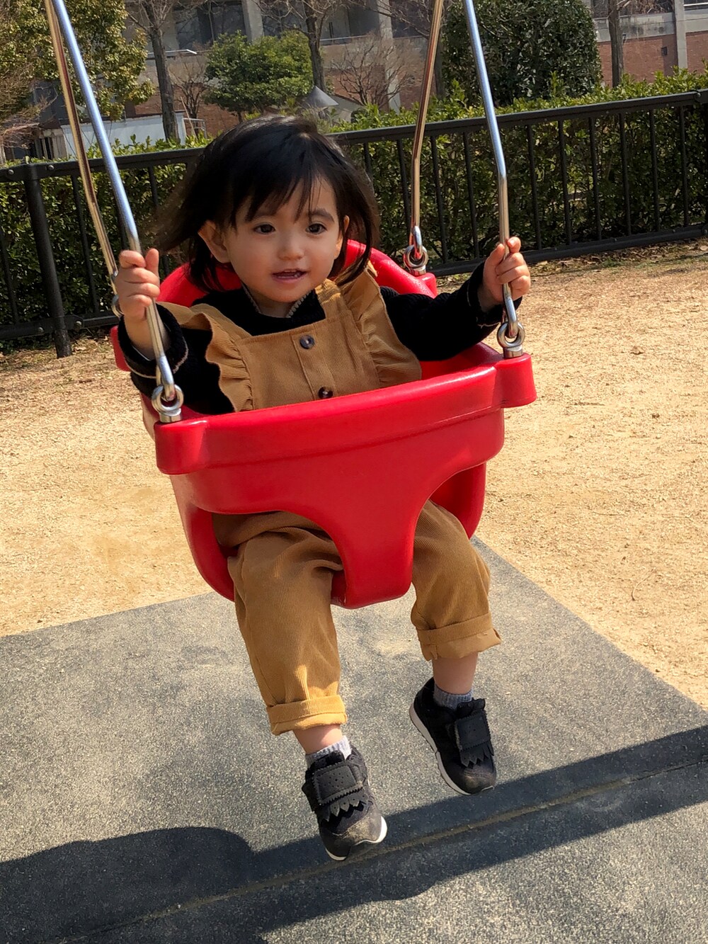 ブラック系のスニーカー、オレンジ系のサロペット/オーバーオール、ブラック系のニット/セーターを着用したキッズの春コーディネートの2枚目の写真