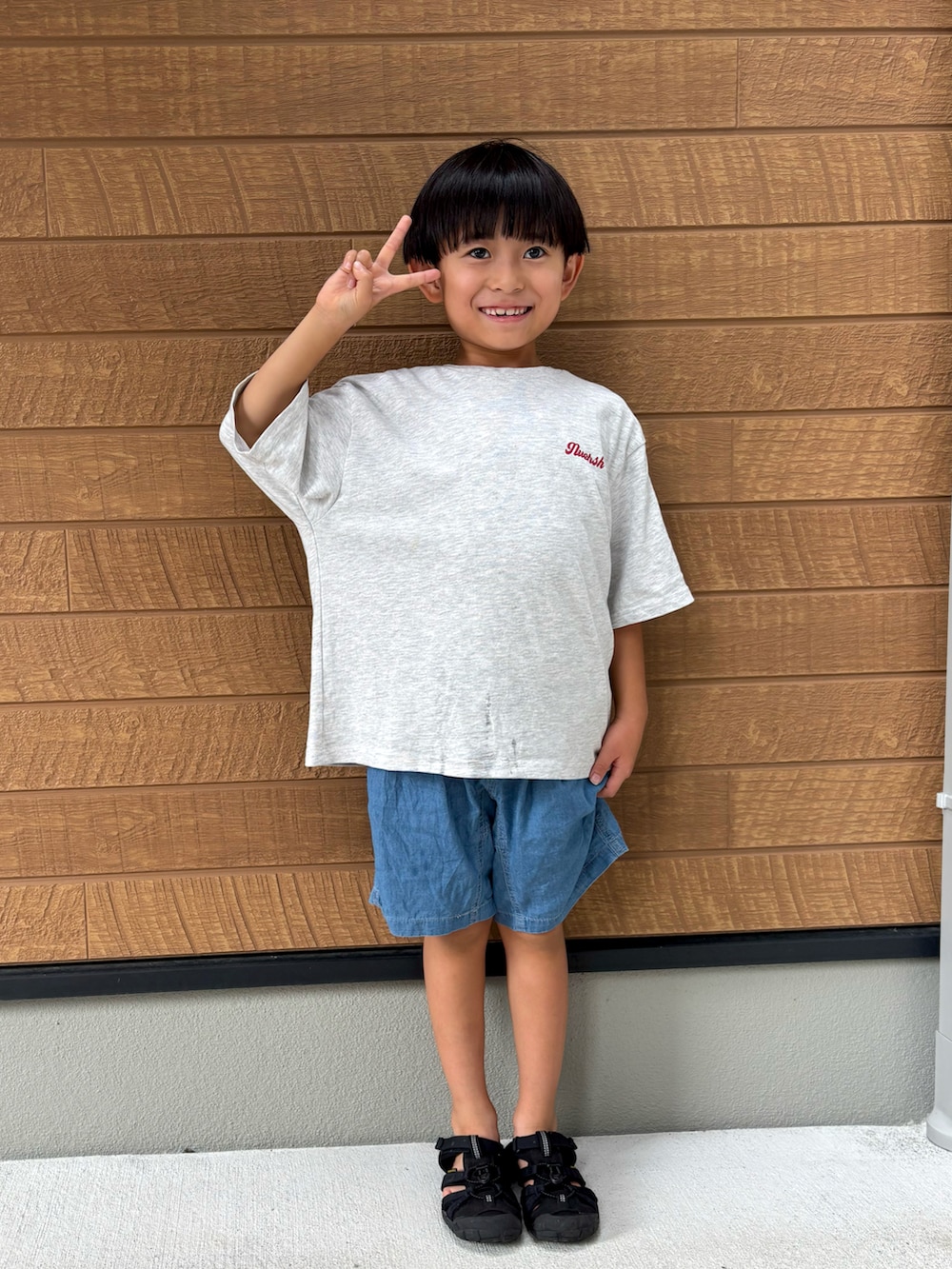 グレー系のTシャツ/カットソー、ブルー系のデニムパンツ、ブラック系のサンダルを着用したキッズの秋コーディネートの2枚目の写真