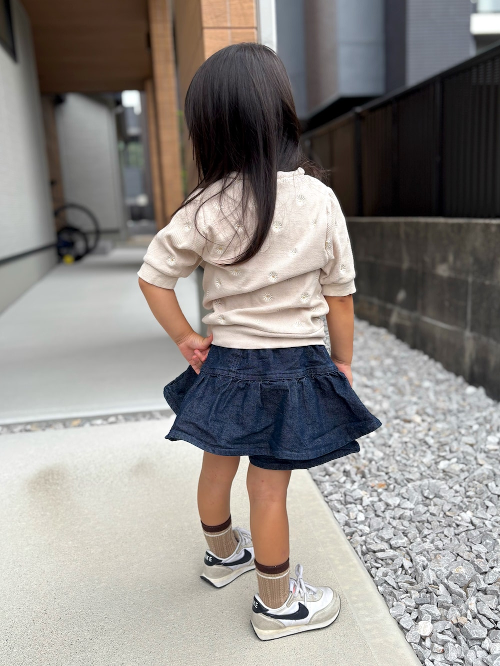 ベージュ系のトップス、ブルー系のデニムパンツ、ホワイト系のスニーカーを着用したキッズの秋コーディネートの2枚目の写真