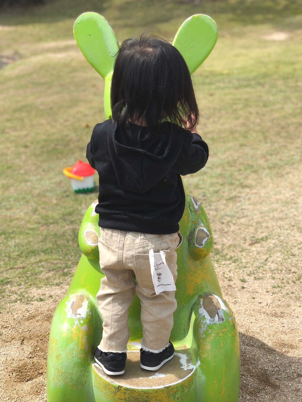 ブラック系のパーカー、ベージュ系のデニムパンツ、ブラック系のスニーカーを着用したキッズの春コーディネートの3枚目の写真