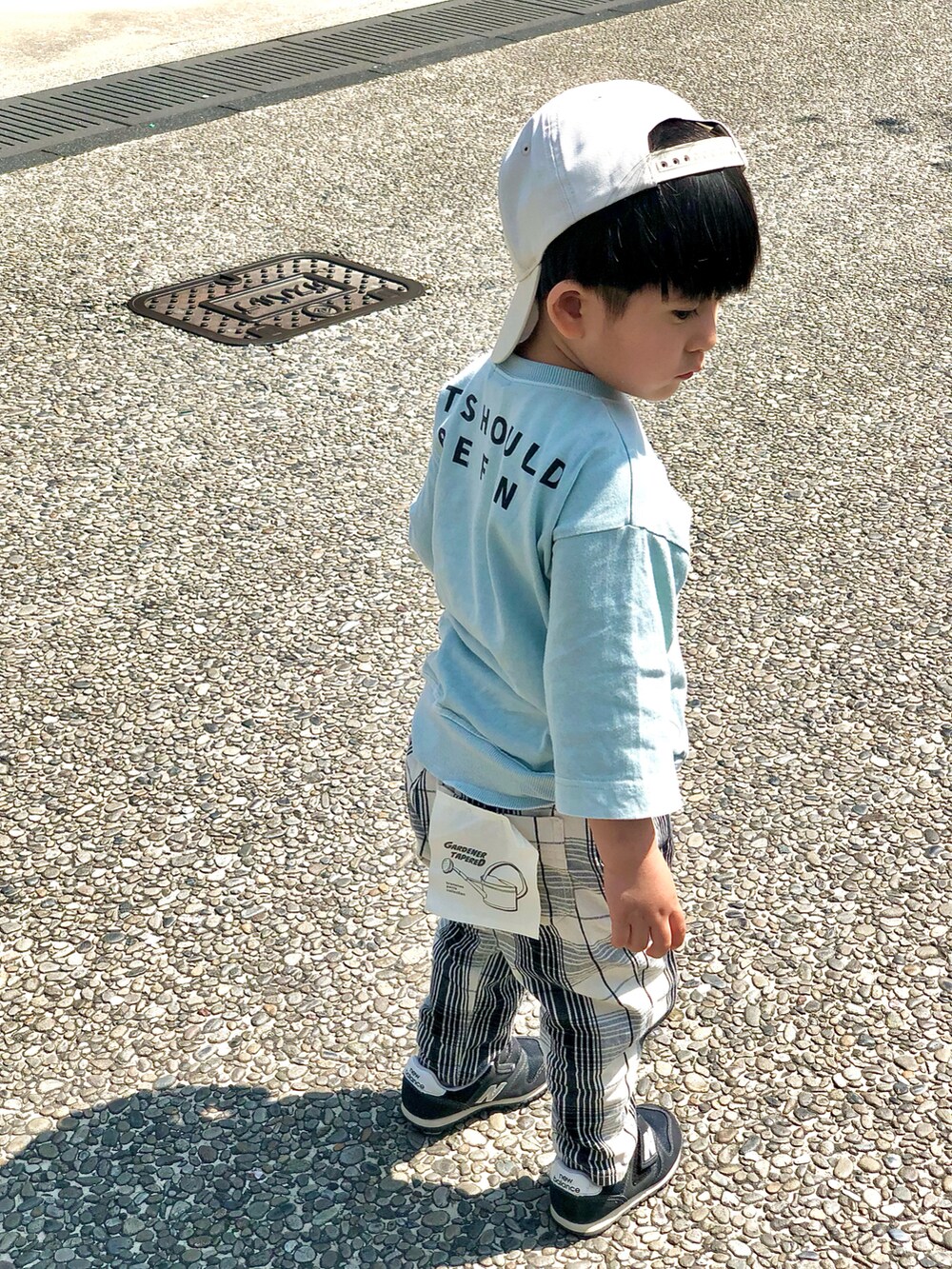 ホワイト系のチノパンツ、グリーン系のTシャツ/カットソー、ブラック系のスニーカーを着用したキッズの春コーディネートの2枚目の写真