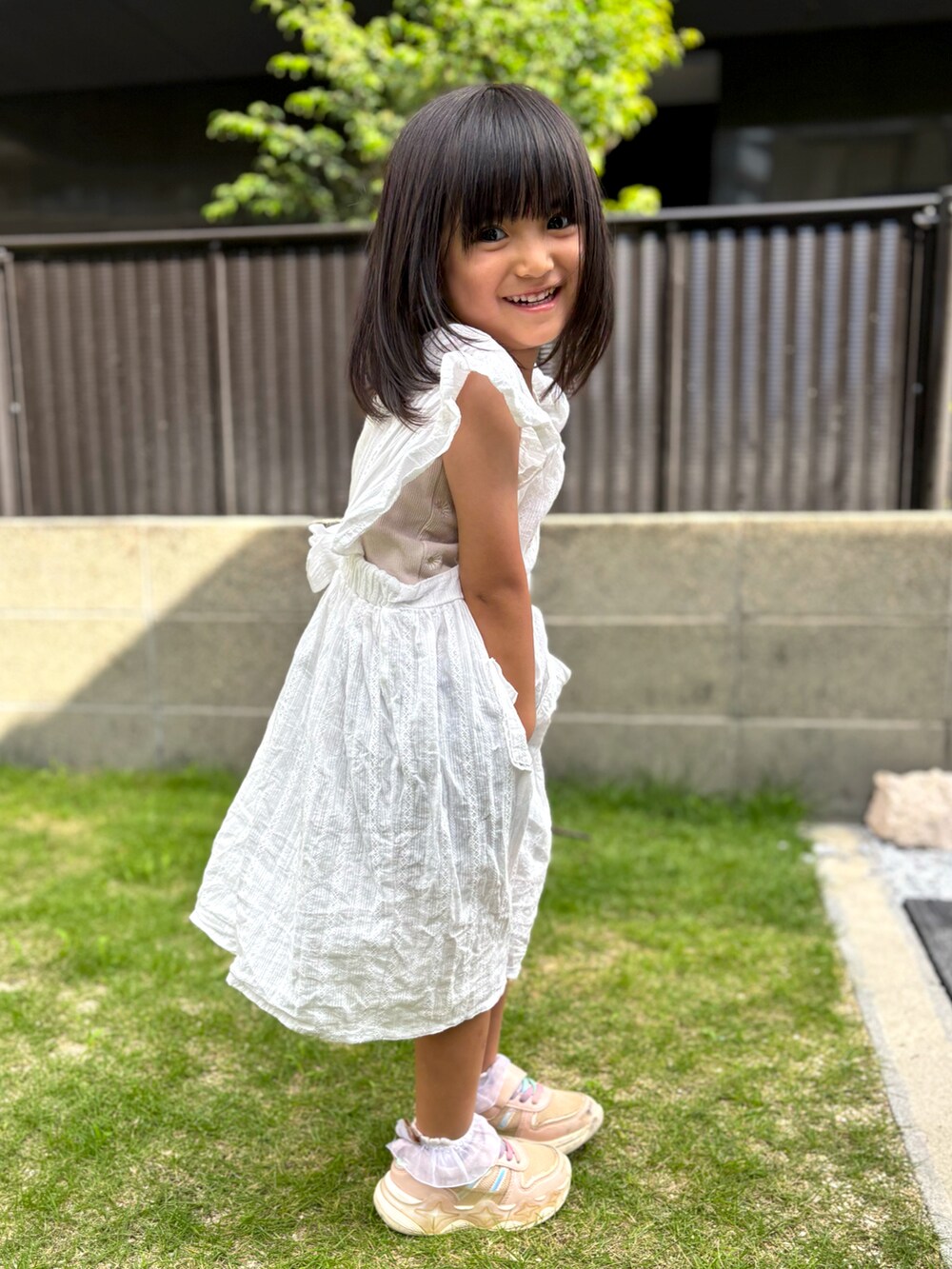 ピンク系のスニーカー、ホワイト系のワンピースを着用したキッズの夏コーディネートの4枚目の写真