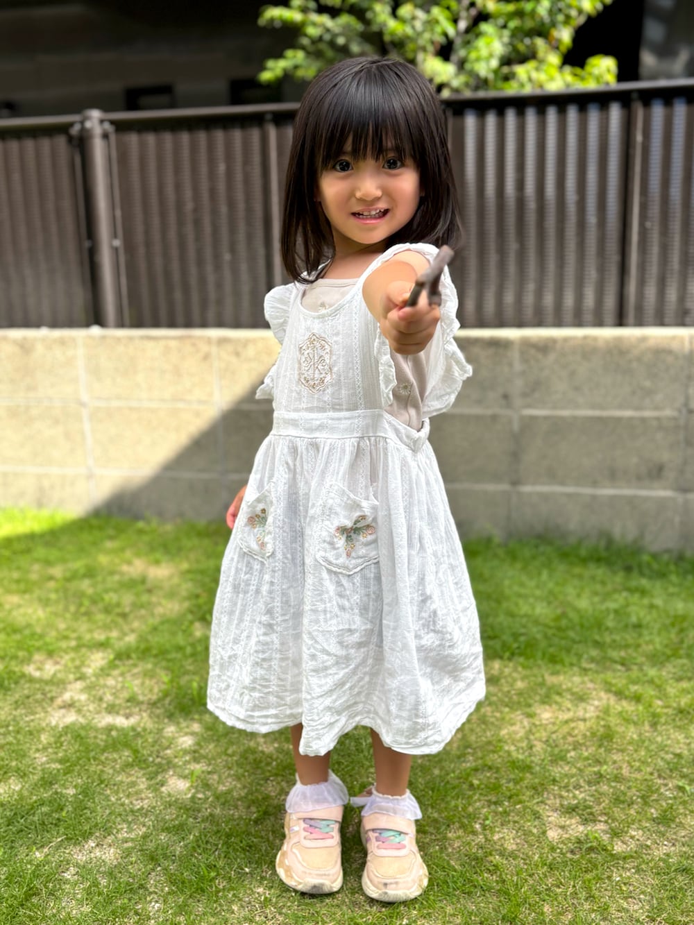 ピンク系のスニーカー、ホワイト系のワンピースを着用したキッズの夏コーディネートの3枚目の写真