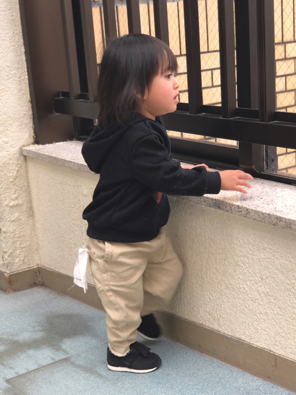 ブラック系のパーカー、ベージュ系のデニムパンツ、ブラック系のスニーカーを着用したキッズの春コーディネートの4枚目の写真